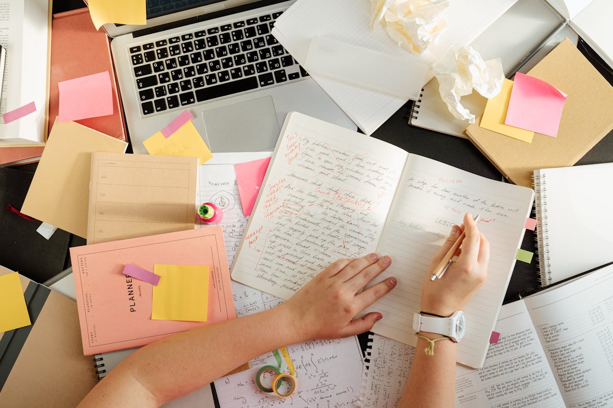 Overhead view of a person organizing research notes and study materials at a desk - representing academic writing where APA style is used