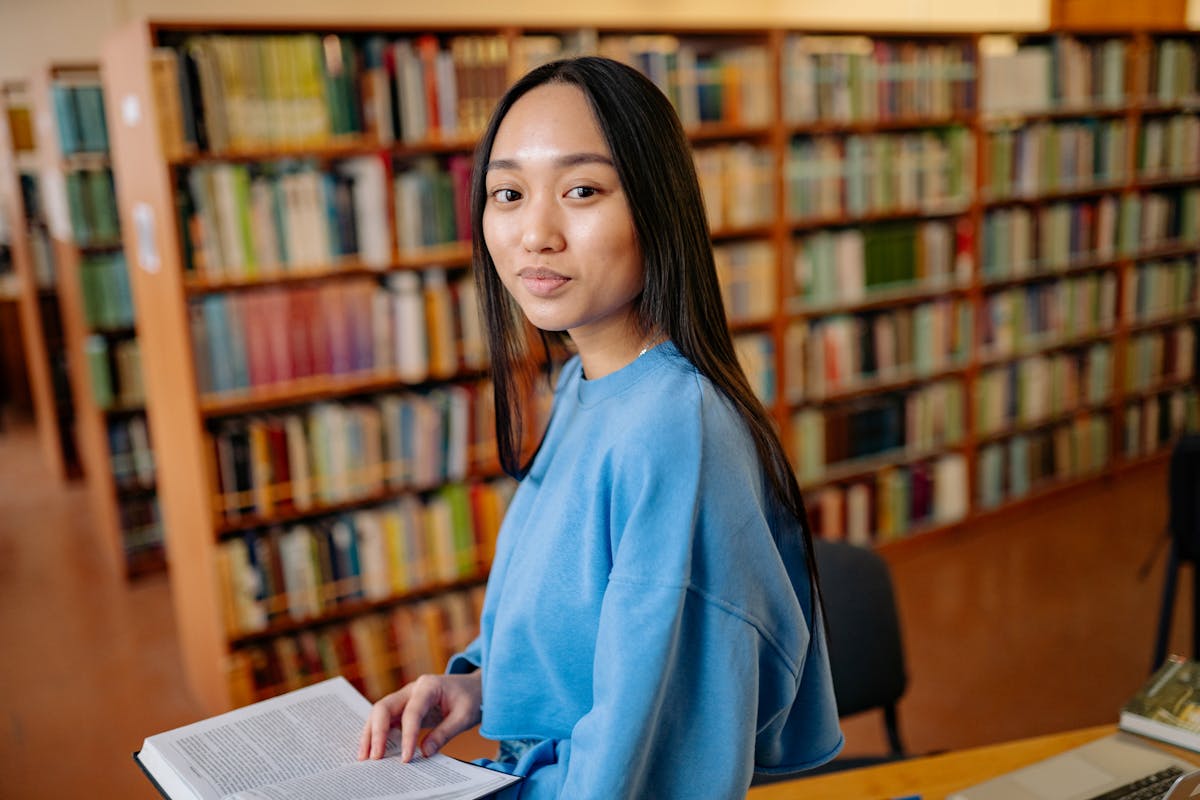 Young woman reading a book in a library - representing humanities writing where MLA style is used