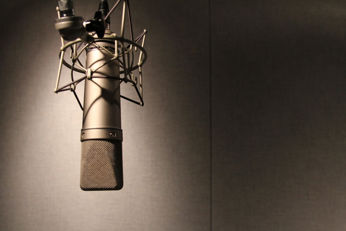 A professional podcast microphone on a desk in a recording studio