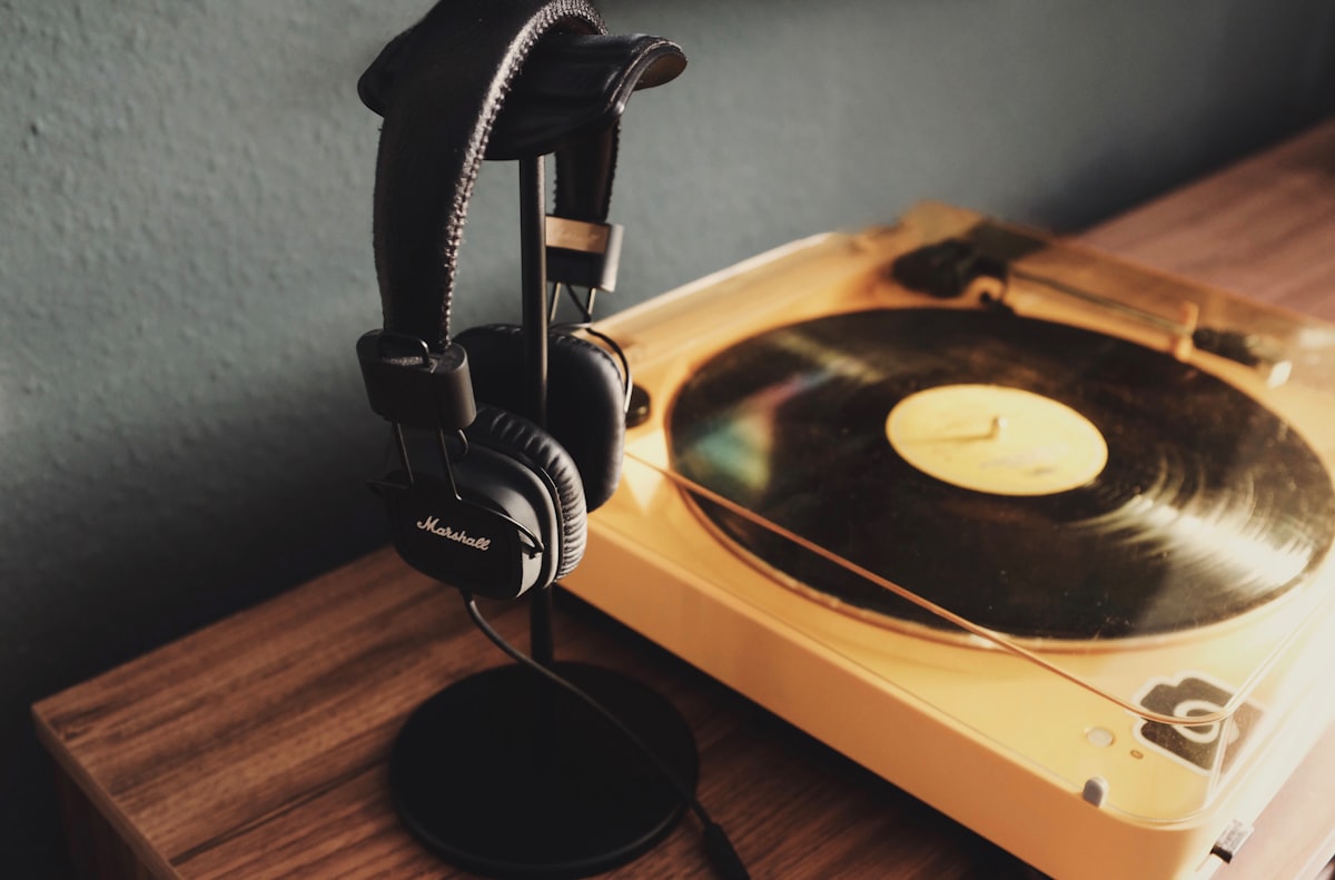 A turntable with a vinyl record and headphones on a wooden surface