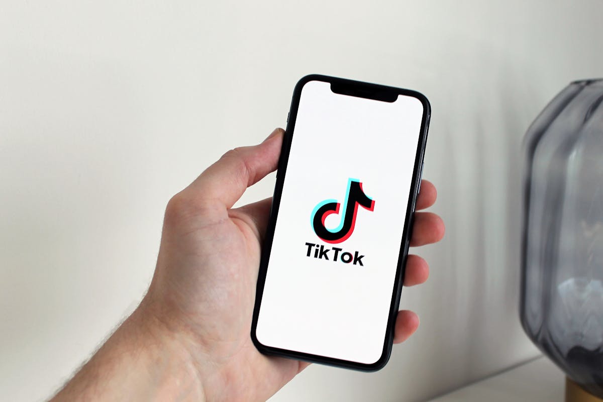 Hand holding smartphone displaying the TikTok app logo